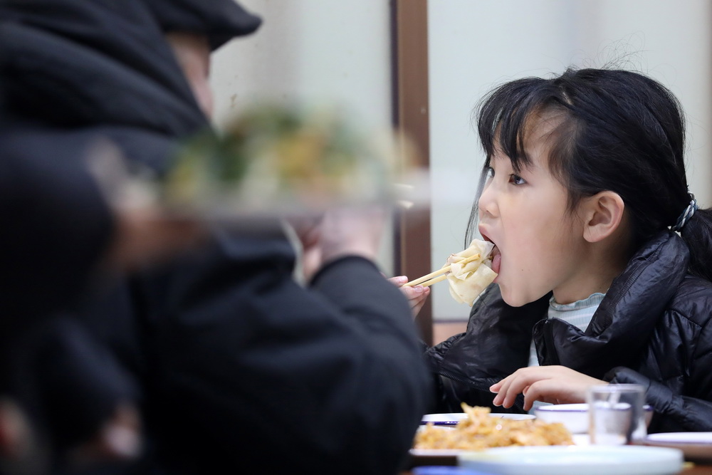 2月2日晚，一位小朋友在劉丹家的春餅店裡吃春餅。
