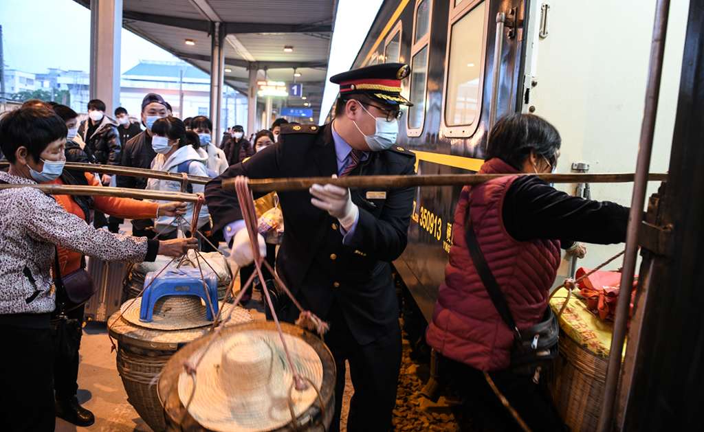 2月5日，在廣東省廉江火車站，乘務人員幫助挑擔的果農登上5534次列車。新華社記者 張愛林 攝