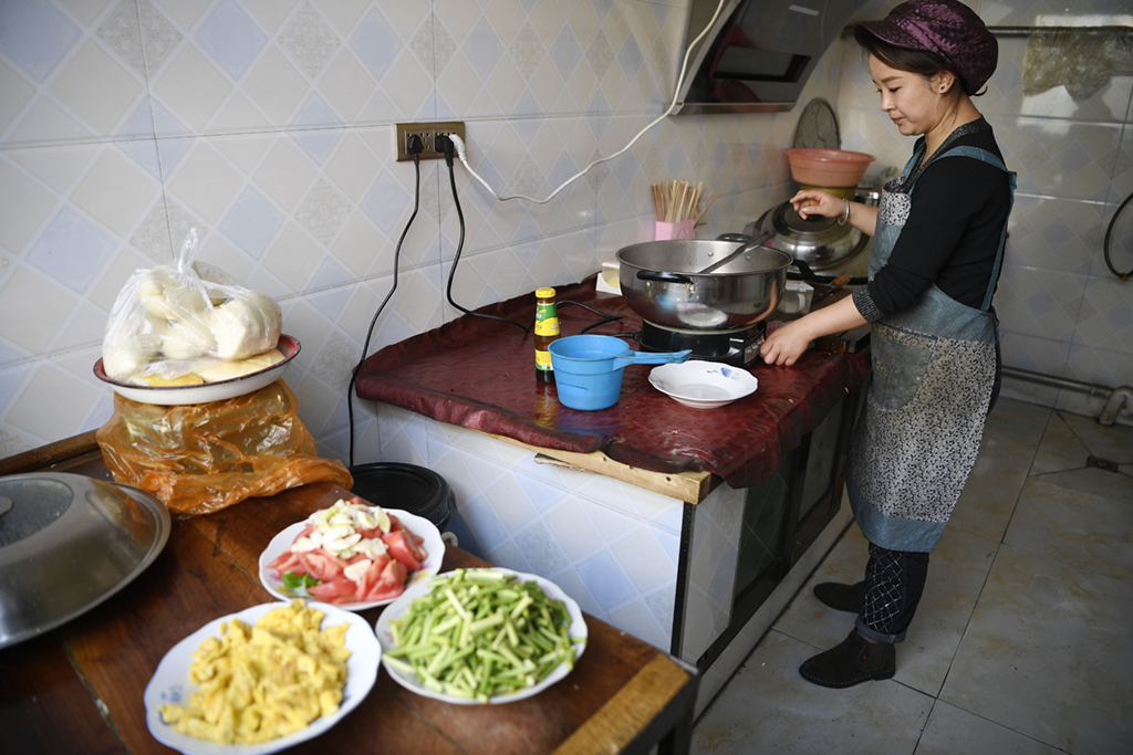 2月11日，張俊明的兒媳在濱河家園移民村家中廚房裡為家人准備午飯。新華社記者 王鵬 攝