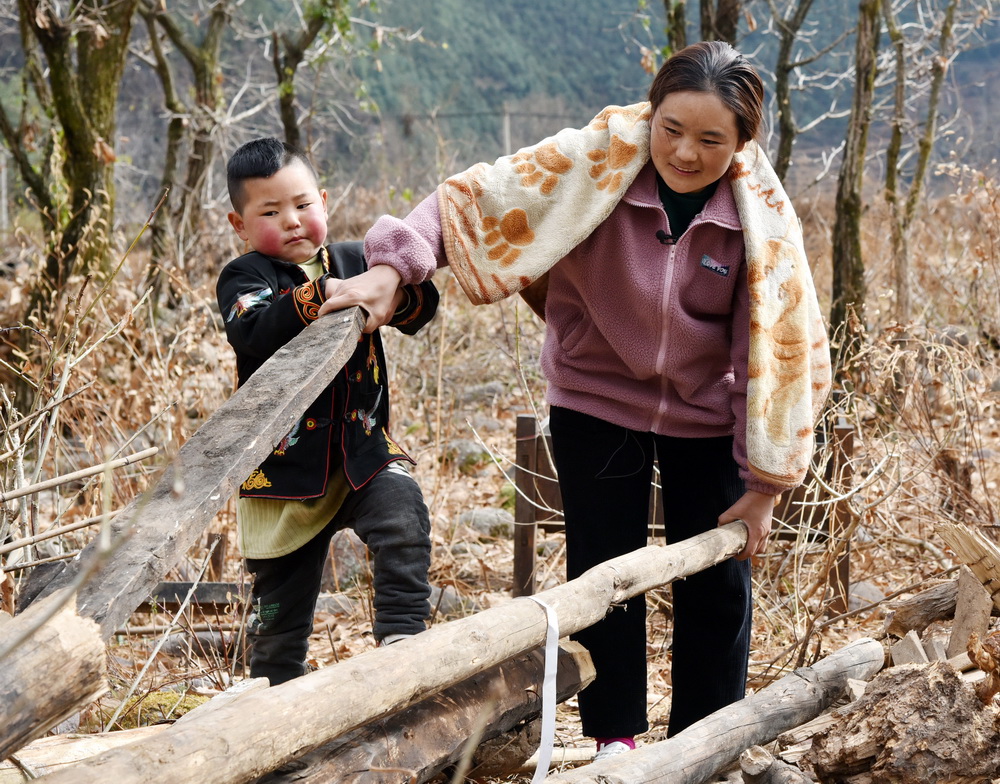 2月16日，巴木玉布木和兒子巫其布吉在收拾土坯房拆除后的房梁和木板。