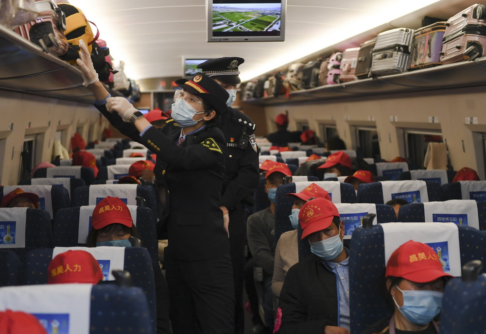 2月21日，在蘭州西開往福州的G1901次列車上，乘務員為務工人員整理行李。