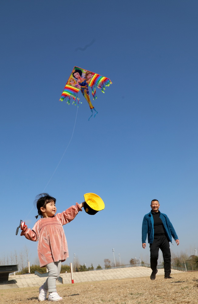 2月21日，在山東省臨沂市郯城縣沭河濱河公園，一名小女孩在家長的陪伴下放風箏。新華社發（張春雷 攝）