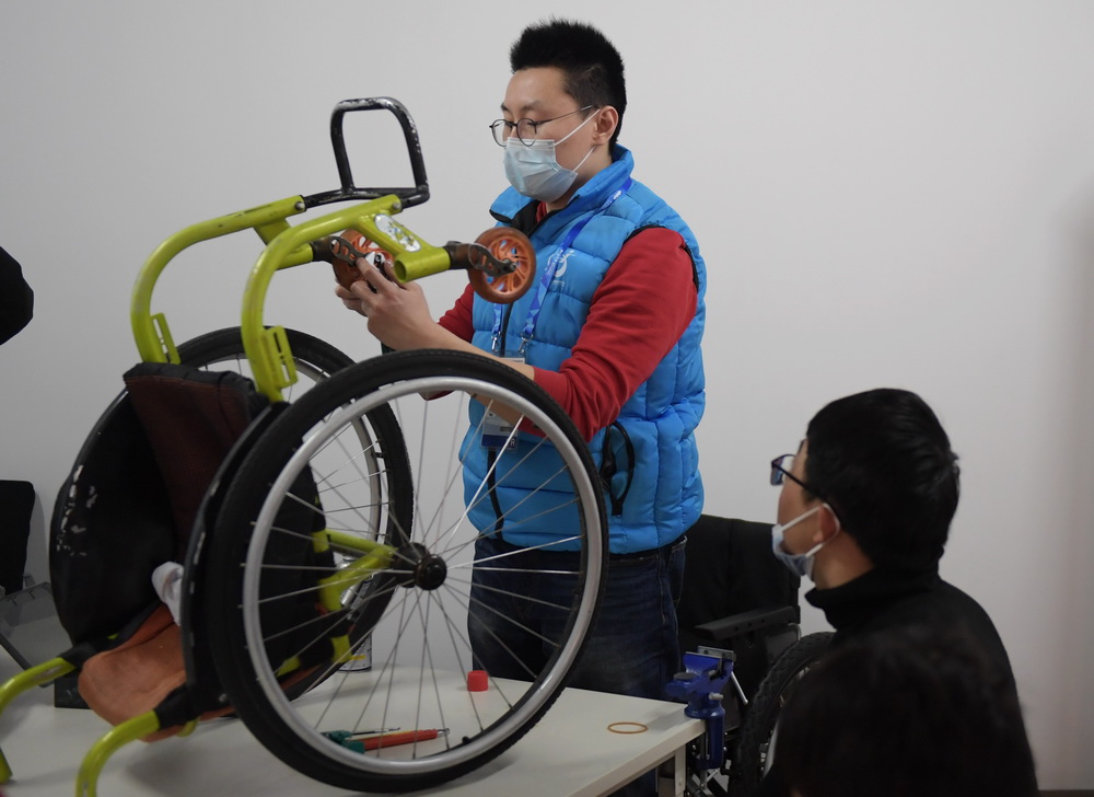 2月23日，延庆赛区国家高山滑雪中心的工作人员正在为残疾人运动员调整轮椅。