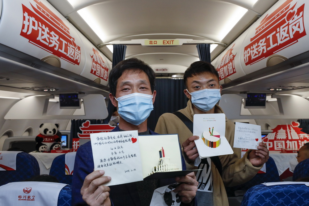 2月23日，在成都開往廣州的川籍農民工返崗專機上，當天過生日的乘客蒲育園（左）、張青鬆展示四川航空送給他們的生日卡等生日禮物。