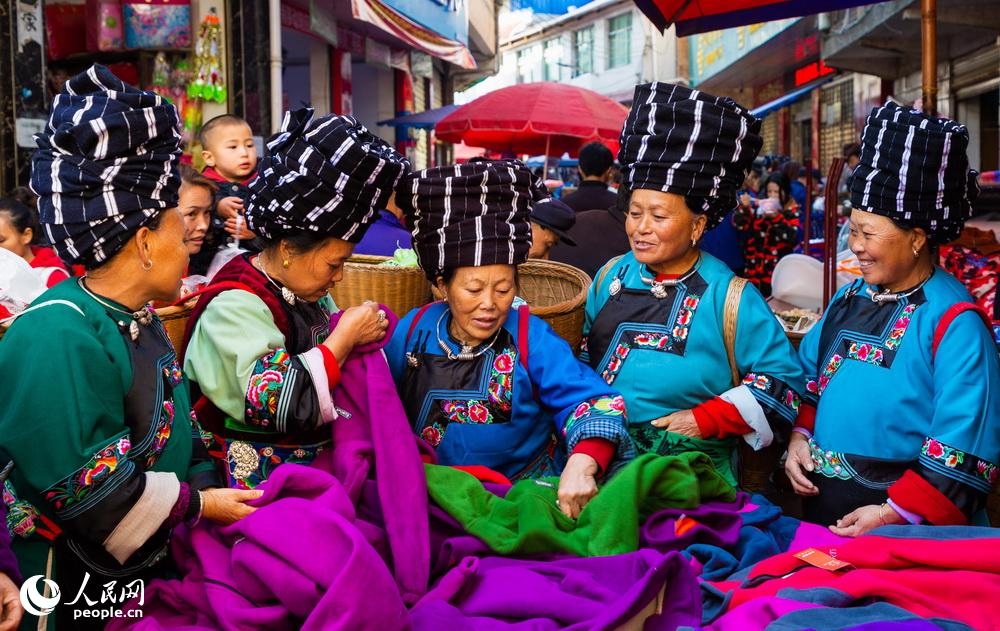 人潮涌動的集市上，一群苗族婦女正在挑選心儀的面料。林森2018年11月拍攝於湘西鳳凰縣禾庫鎮。