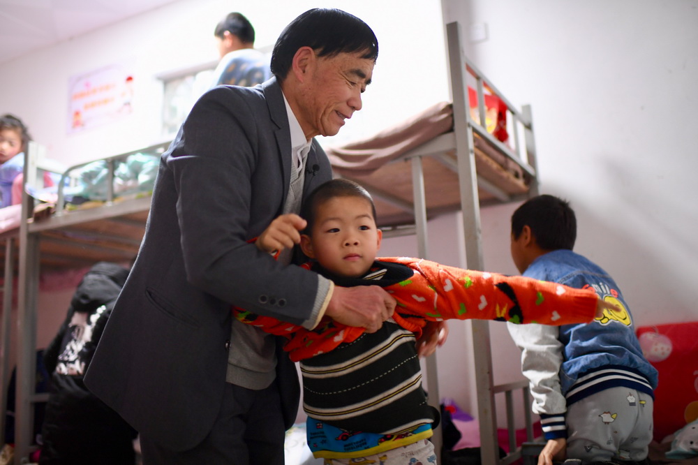 3月1日，西津畬族小學校長庄桂淦幫助寄宿的孩子起床穿衣。