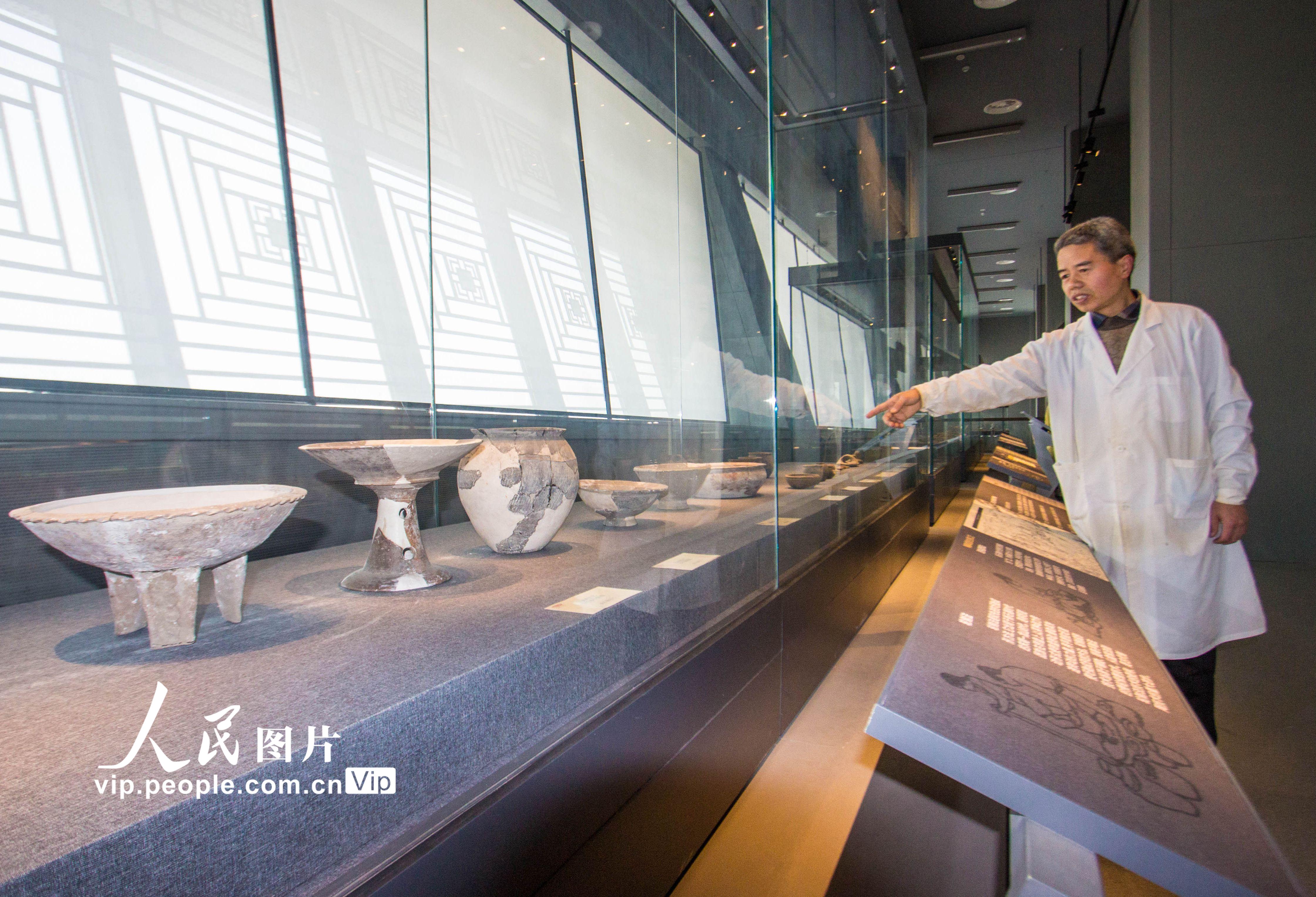 3月30日，河南省南陽市博物館新石器時代陶器展廳，文物修復技術人員在查看陳列的文物。