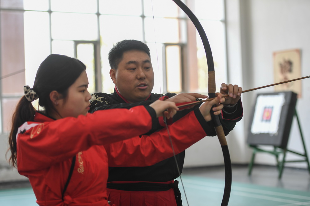 3月24日，湖南省長沙師范學院的射藝課老師劉紅星（右）在射藝課上指導學生握弓。