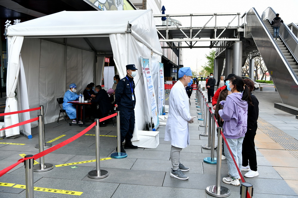 4月7日，路過接種點的市民向醫護人員咨詢疫苗接種相關知識。新華社記者 李鑫 攝