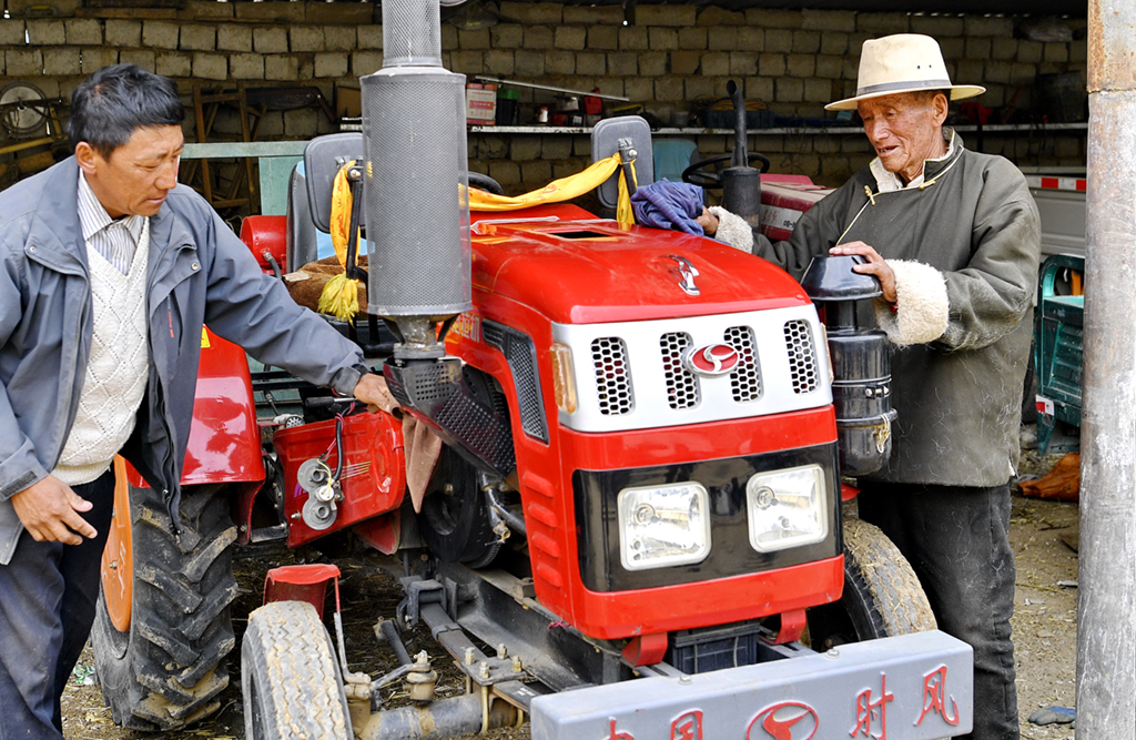 多扎木（右）在擦拭自家的拖拉機（3月20日攝）。