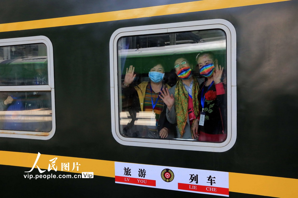 4月13日，游客在專列裡向站台上的工作人員揮手告別。 