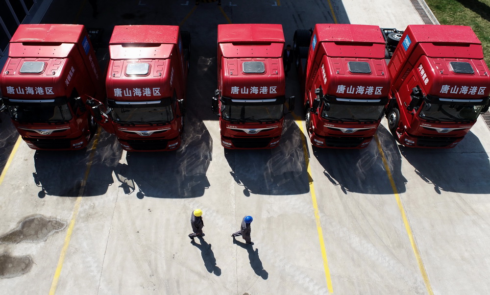 4月14日，在河北唐山海港經濟開發區，工人從准備投入使用的氫燃料電池重卡前走過（無人機照片）。