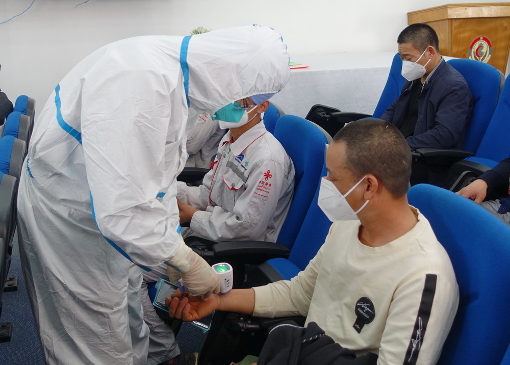 4月14日，在突尼斯首都突尼斯市，工作人員為一名准備接種新冠疫苗的中國公民檢查體溫。