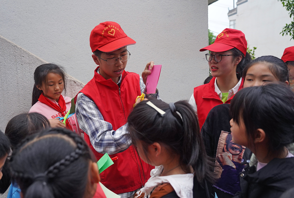 江西科技師范大學的志願者教孩子們剪紙（4月20日）。