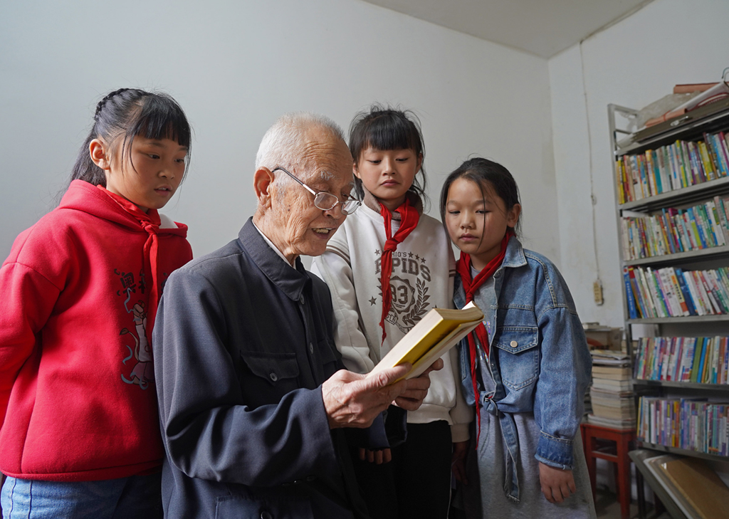 繆延相（左二）在校外輔導站的圖書室和孩子們一起看書（4月20日攝）。