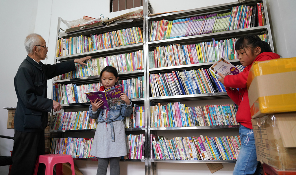 繆延相（左一）在校外輔導站的圖書室整理書籍（4月20日攝）。