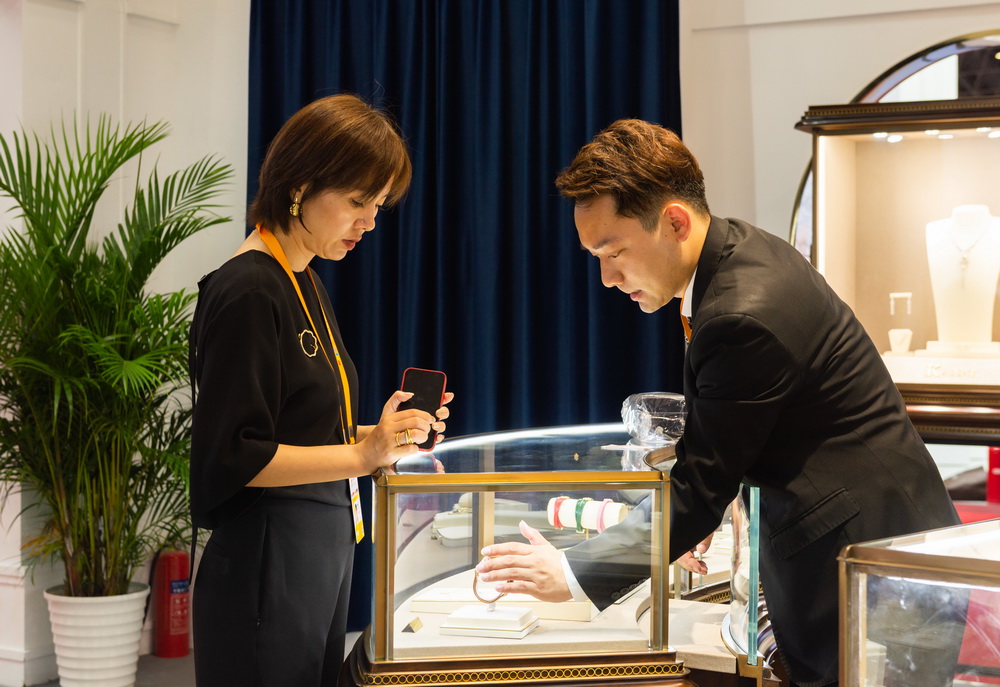 5月7日，在海南國際會議展覽中心珠寶展區，工作人員（右）向參觀者介紹參展商品。新華社記者 周佳誼 攝