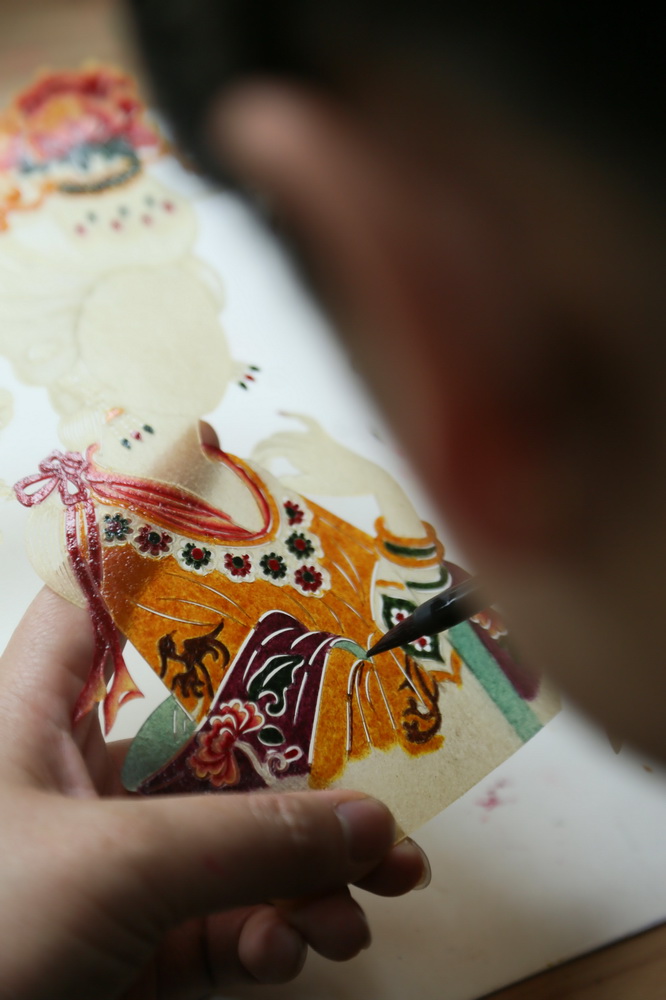 5月8日，工作人员在陕西省渭南市华州区少华山国际皮影博览园为皮影上色。新华社发（王智超 摄）