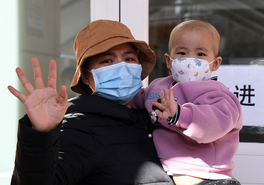 在首都儿科研究所附属儿童医院，哆哆与母亲在进入住院楼前向家人挥手（2月22日摄）。新华社记者 任超 摄