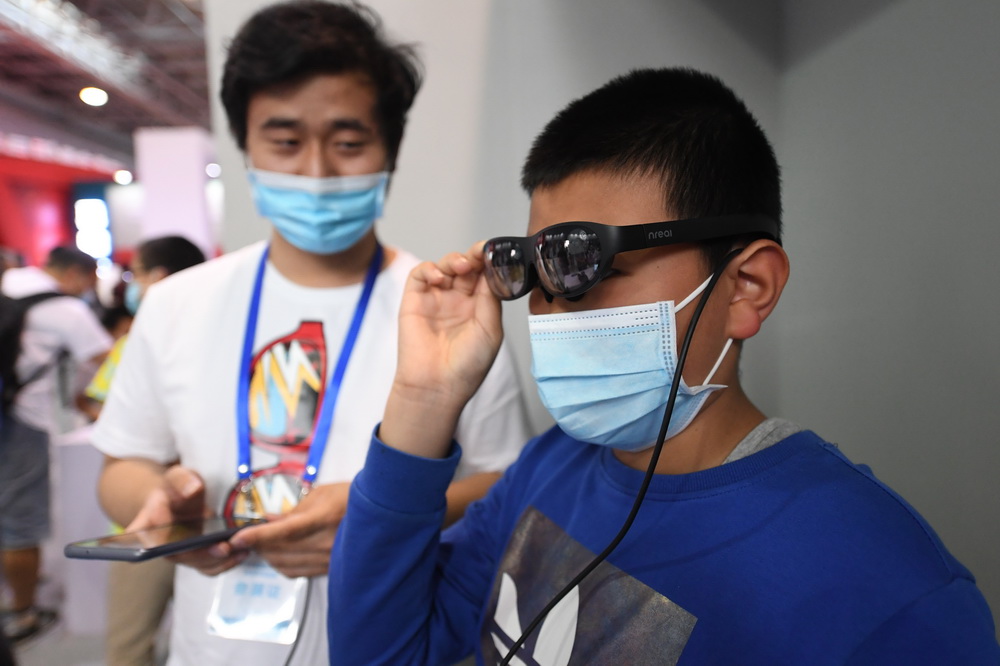 5月23日，在北京科技周活动主场室内主题展区，观众（右）在体验混合现实智能眼镜。