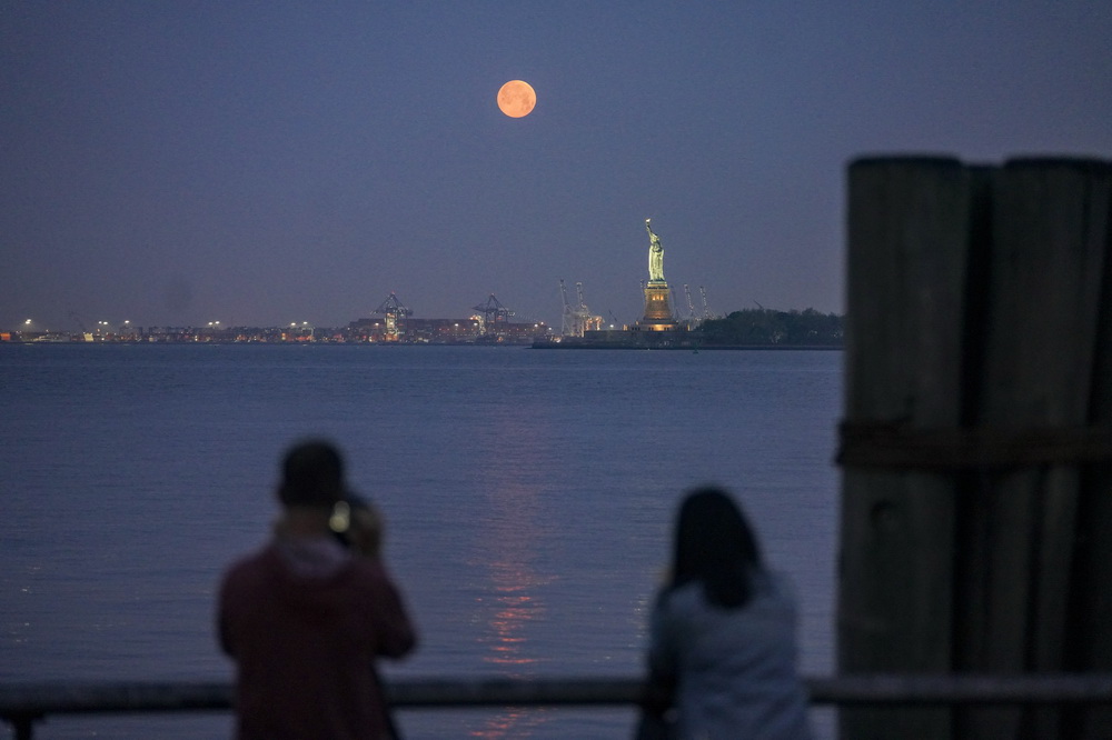5月26日，在美國紐約，一輪圓月出現在自由女神像上方的天空。新華社記者 王迎 攝