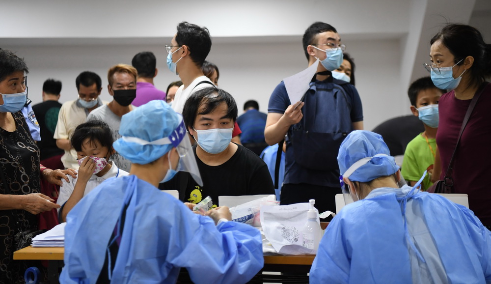 在廣州荔灣體育館核酸檢測點，前來核酸檢測的市民等待醫務人員核對信息、分發病毒採樣管（5月26日攝）。