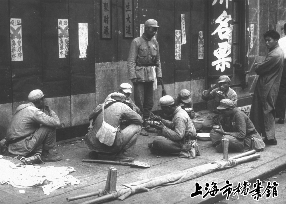 進入上海后，解放軍嚴守紀律，不入民房，在街邊吃飯（資料照片）。新華社發（上海市檔案館提供）