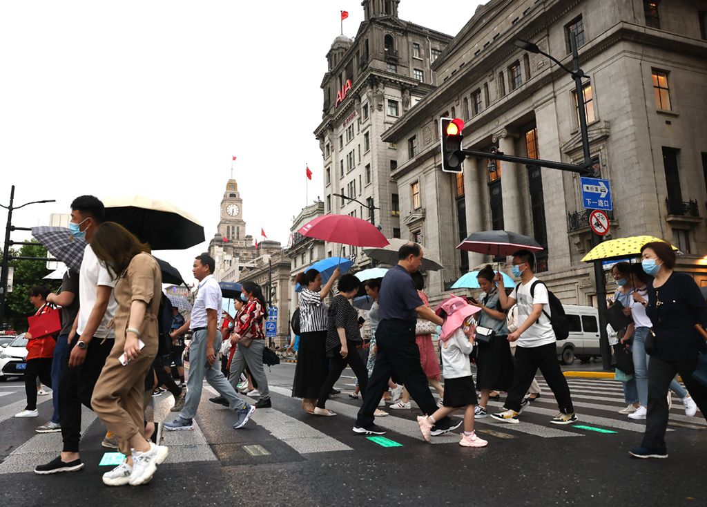 6月10日，游客行走在雨中的上海外灘。