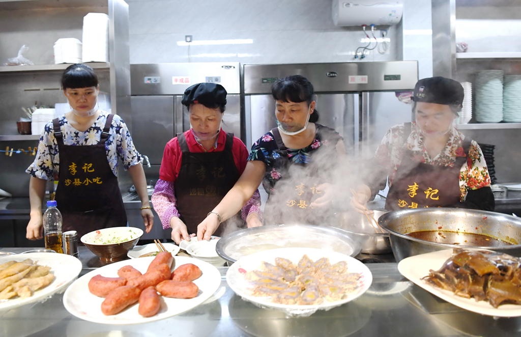 6月10日，福建三明市沙縣區一家小吃店工作人員在為客人准備特色小吃。
