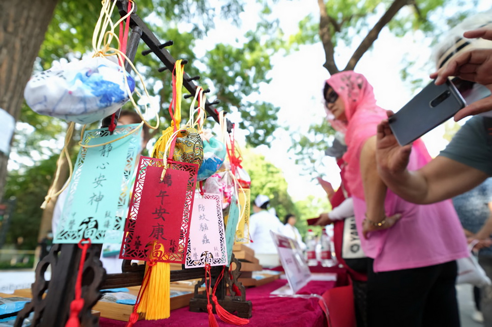 6月12日，在北京龍潭公園，人們觀看展位上的中藥百草香囊。