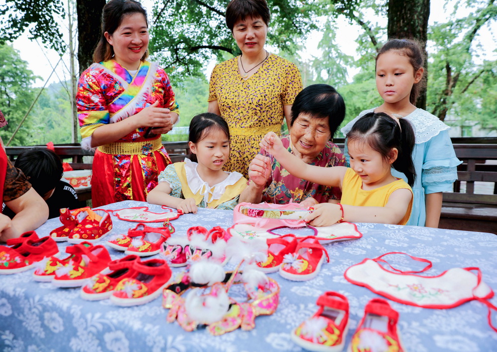6月13日，在浙江省湖州市長興縣小浦鎮方一村，當地的非遺傳承人教孩子們制作老虎鞋、老虎帽。新華社記者 徐昱 攝