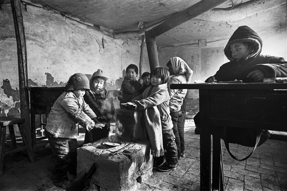 1991年12月，河北省滦平县拉海沟乡大店子村小学，气温骤降至零下20度，孩子们烤烤冻僵的小手继续上课。解海龙摄