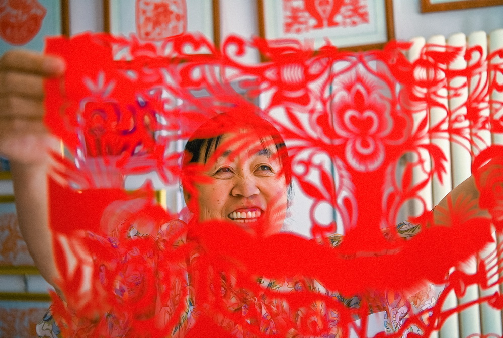 國家級非物質文化遺產“安塞剪紙”項目傳承人余澤玲在展示剪紙作品。蔣雨師攝