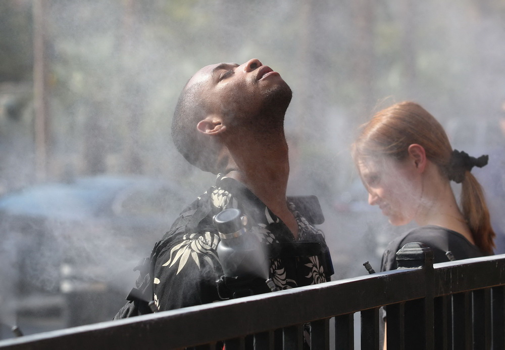 6月16日，人們在美國西部內華達州拉斯維加斯街頭的噴水霧器旁納涼。新華社/法新