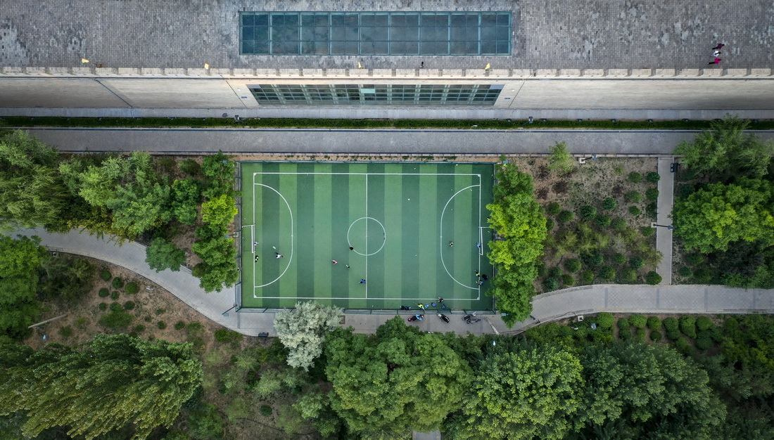 6月18日，宁夏盐池县居民在城墙下的运动场踢足球（无人机照片）。新华社记者 冯开华 摄
