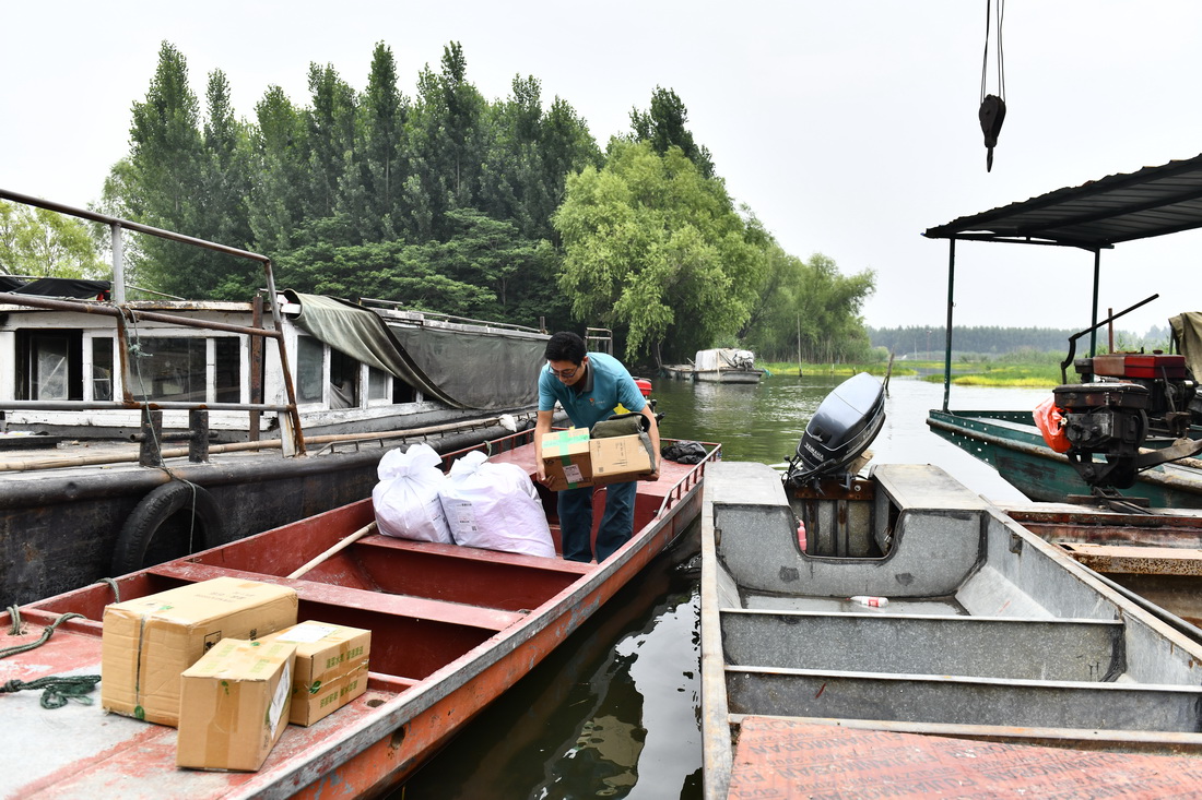 6月20日，在微山縣南陽鎮，郵遞員王少朋往郵船上裝郵件，准備為村民投遞。