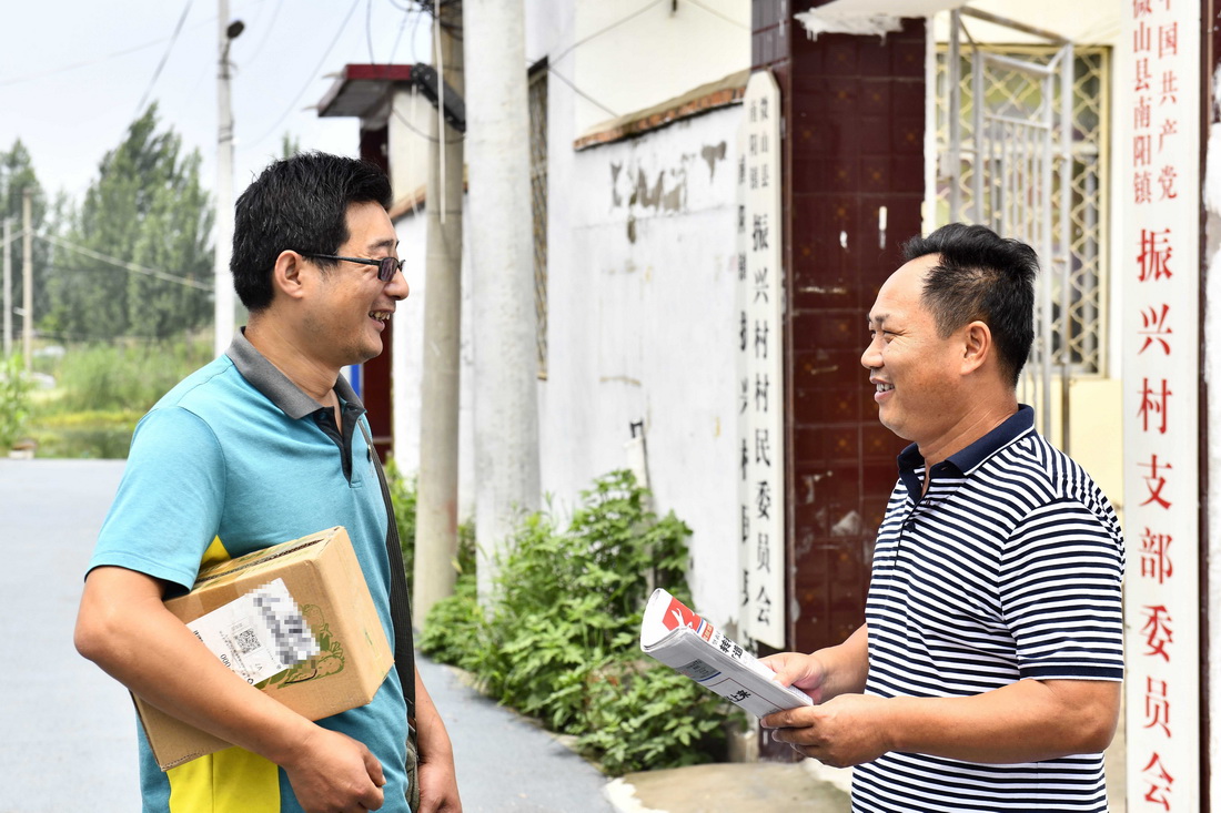 6月20日，在微山縣南陽鎮，郵遞員王少朋為振興村村委會投遞報紙。