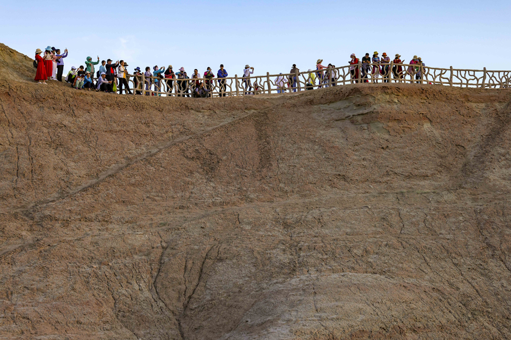 游客在新疆克拉瑪依烏爾禾世界魔鬼城景區欣賞日落（6月21日攝）。新華社記者 胡虎虎 攝