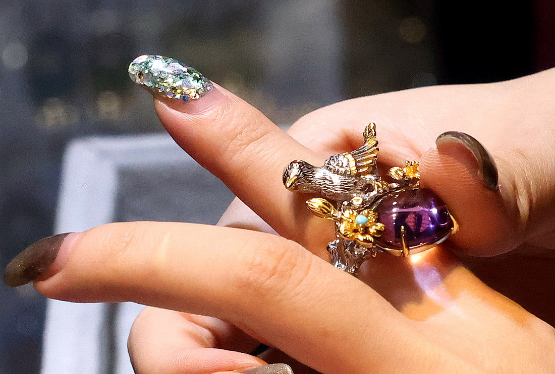 6月24日，参观者在上海国际珠宝首饰展览会上试戴彩色宝石戒指。