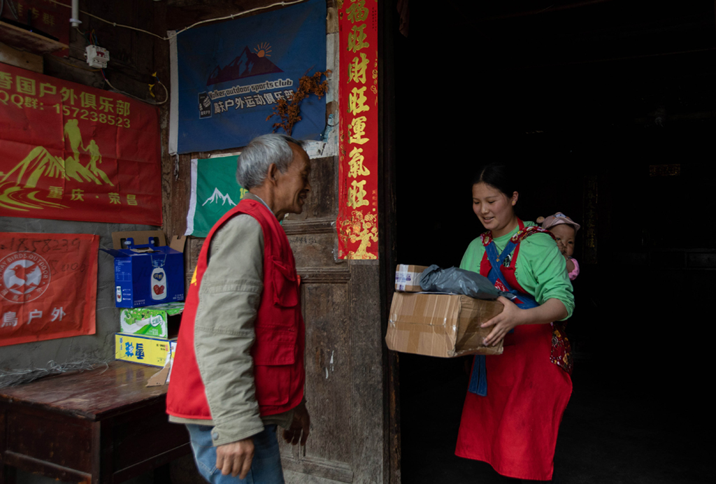 郵政代辦員向開強（左）把包裹送到村民李娟家中（6月23日攝）。