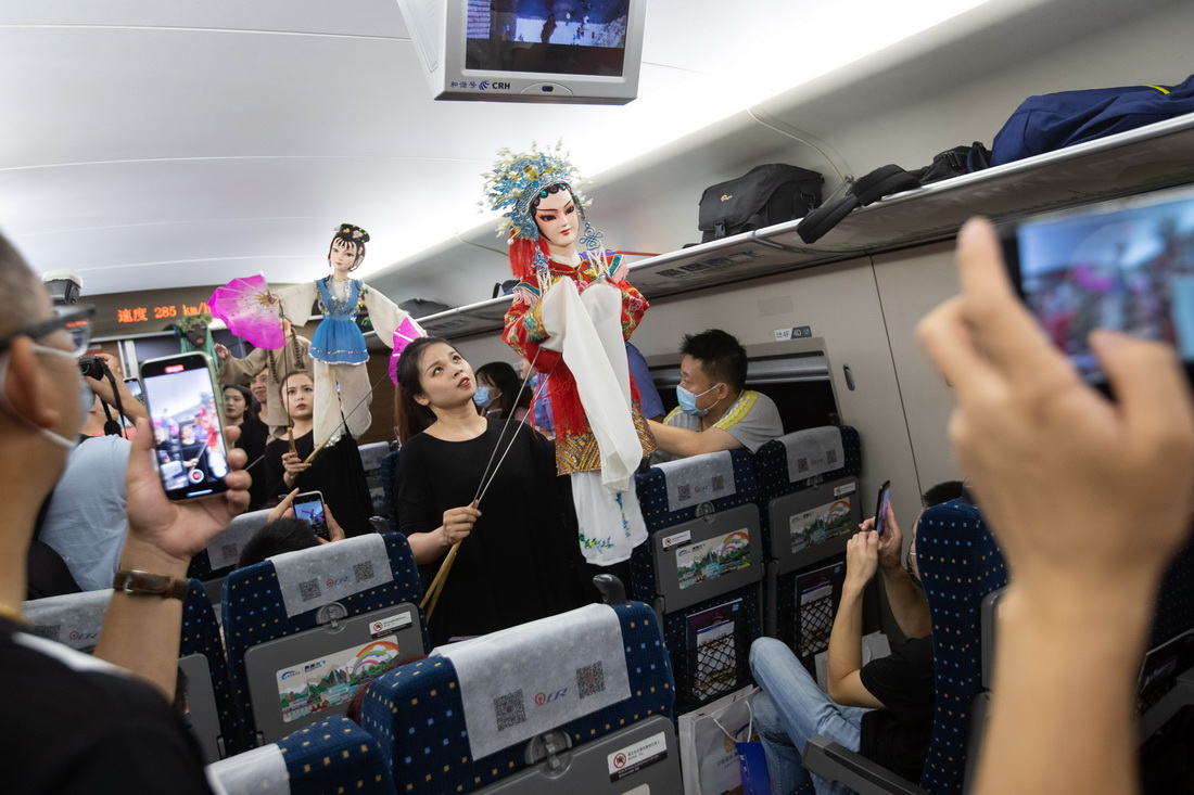 6月28日，在D1758次列車上，演員為乘客表演內江市特色文化節目杖頭木偶戲。新華社記者 江宏景 攝
