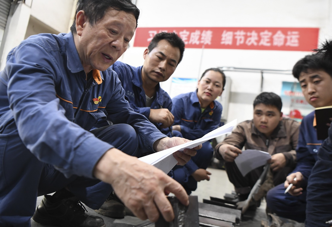 6月17日，艾爱国（左一）在湖南湘潭湘钢高级技工学校焊接实习基地检查学生的焊接作业。新华社记者 薛宇舸 摄