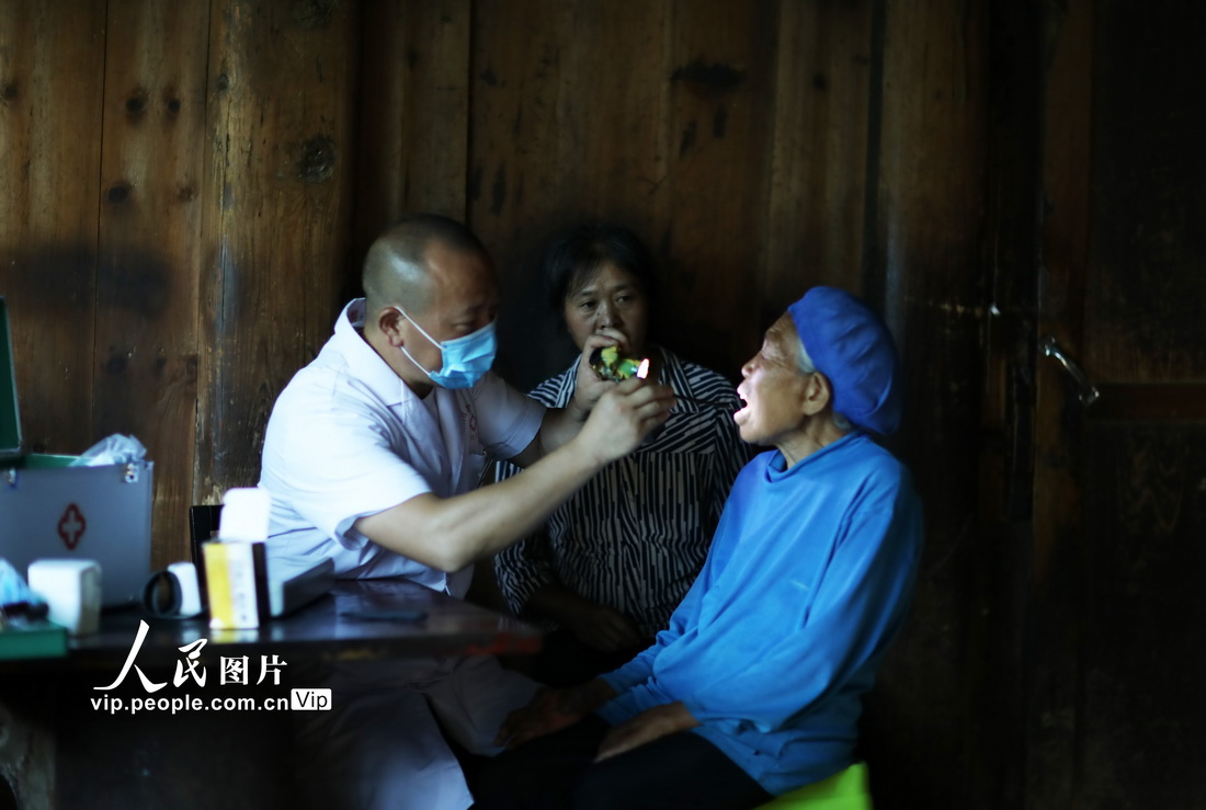 7月10日，在綏陽縣茅埡鎮中坪村，張濤（左）給84歲老人羅永江查看口腔情況。