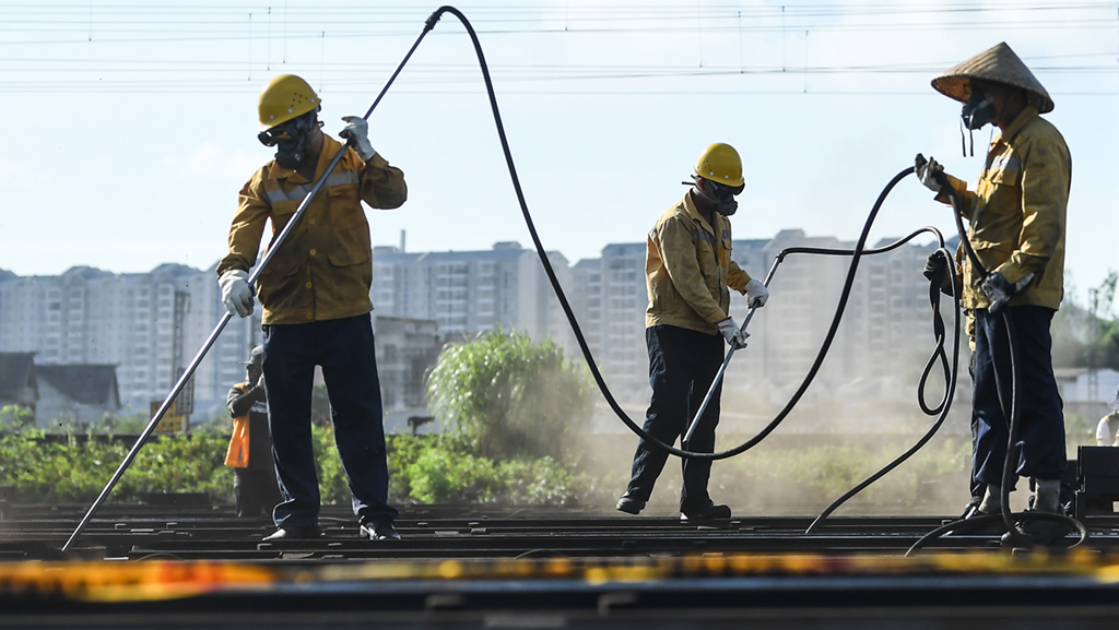 在柳州南编组站，柳州电务段的职工在清除驼峰缓行器设备的灰尘杂质和顽固油泥（7月9日摄）。