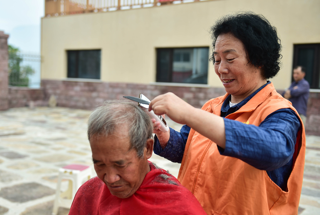 7月7日，在山西省阳城县人参�按澹�栗红连（右）给村里的老人理发。