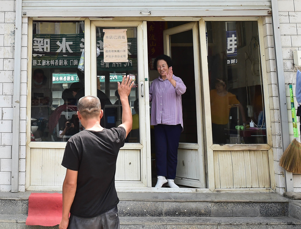 7月6日，在山西省阳城县东关村的红连理发店，栗红连（右）送走理发的客人。
