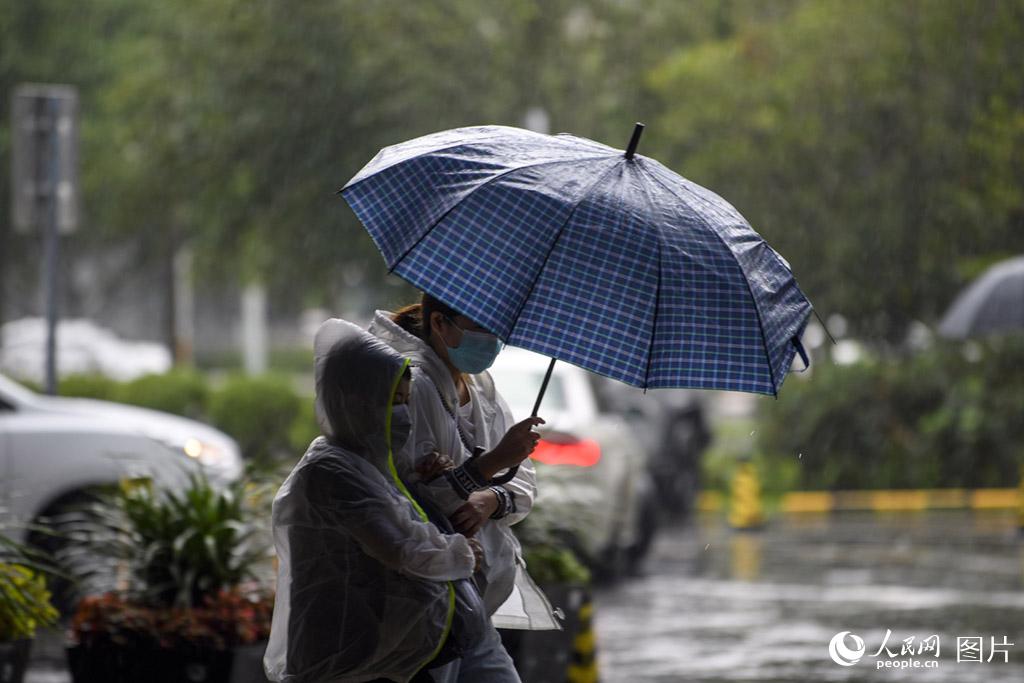 7月12日，北京街头，冒雨赶路的上班族。人民网记者 翁奇羽摄