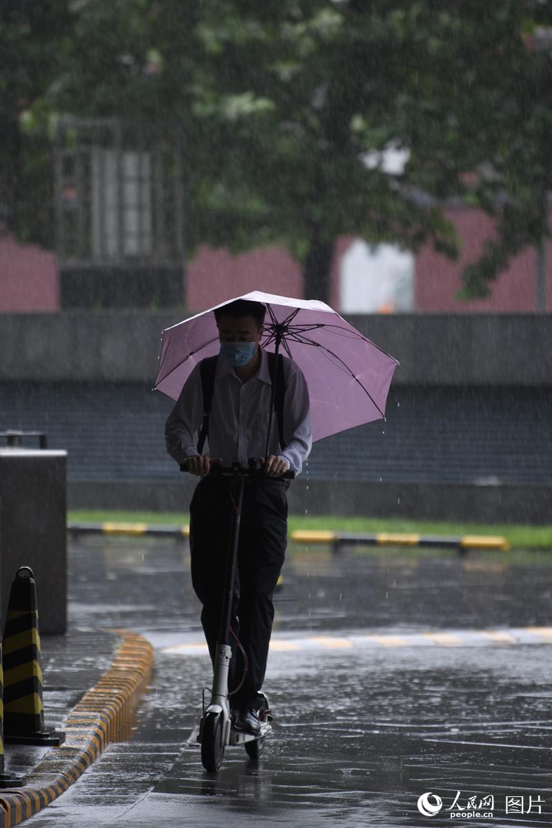 7月12日，北京街头，冒雨赶路的上班族。人民网记者 翁奇羽摄
