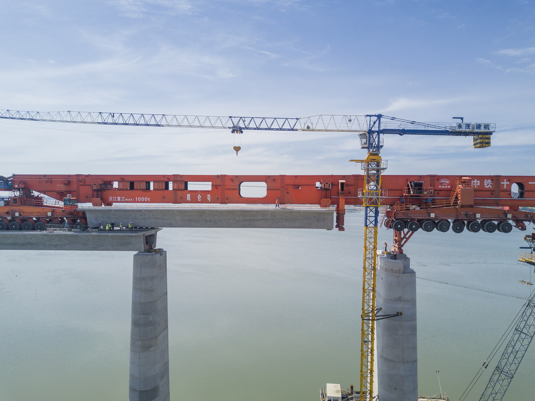 7月11日，在新建福厦铁路湄洲湾跨海大桥建设现场，中铁十一局工人协同“昆仑号”千吨级运架一体机架设该线路最后一孔40米箱梁（无人机照片）。
