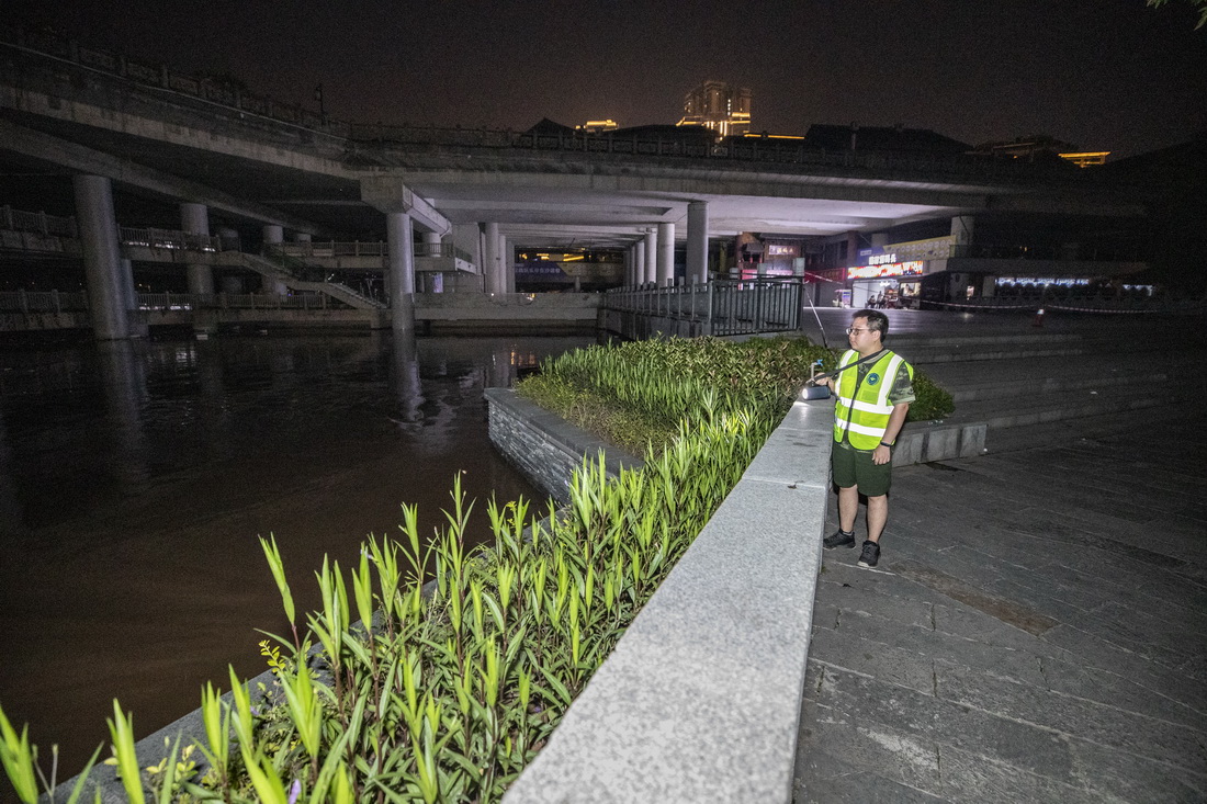 7月12日晚，在重慶沙坪壩區磁器口古鎮，工作人員在嘉陵江沿江區域巡邏，查看水位。